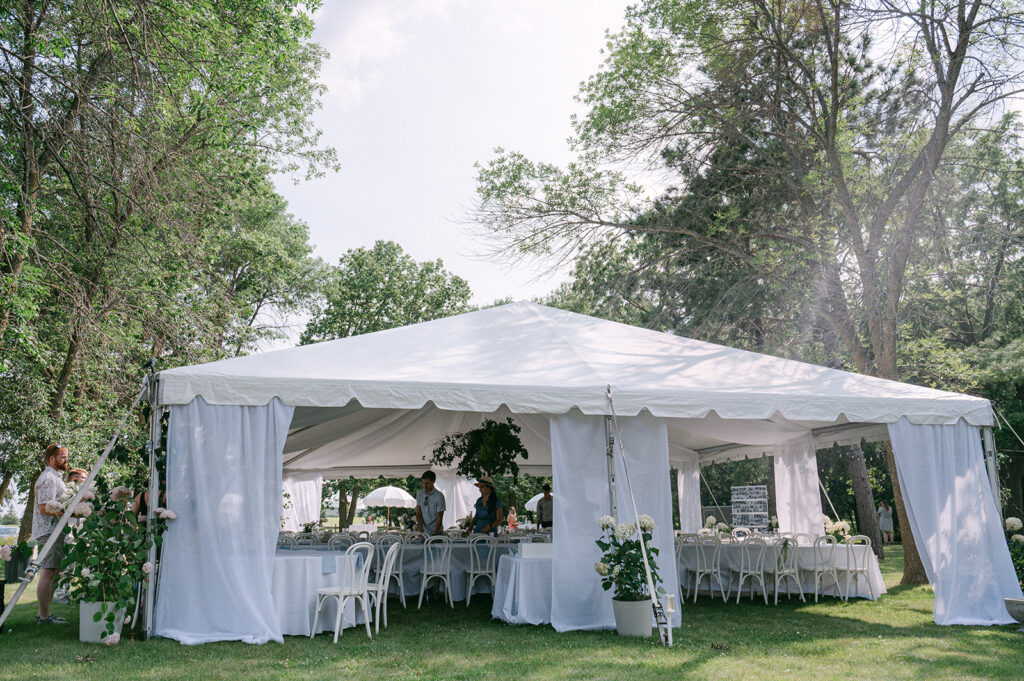 Elegant tented reception showcasing organic details with white linens, floral arrangements in Battle Lake. 