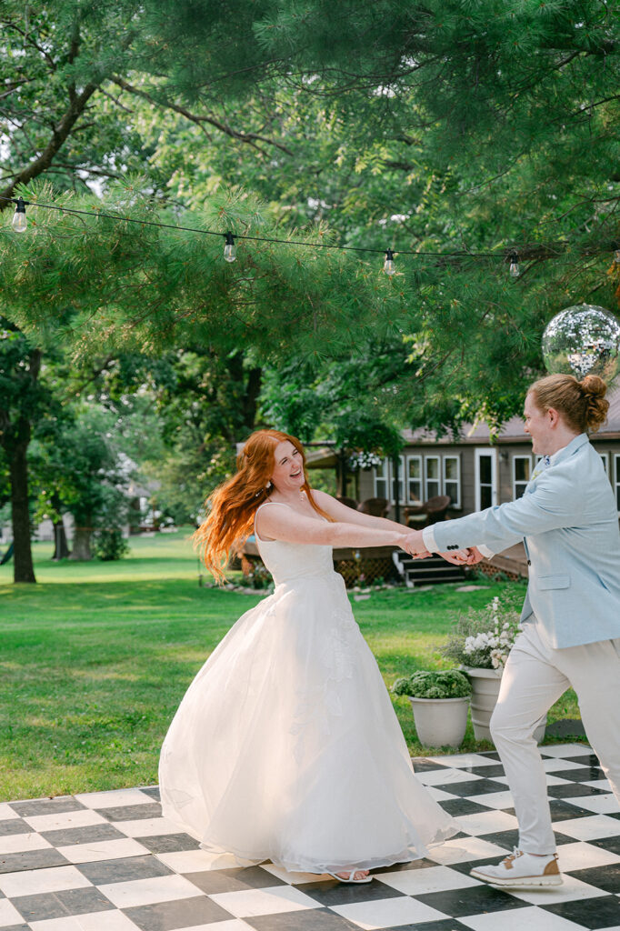 Playful first dance on the checkered dance floor, documentary style photography.