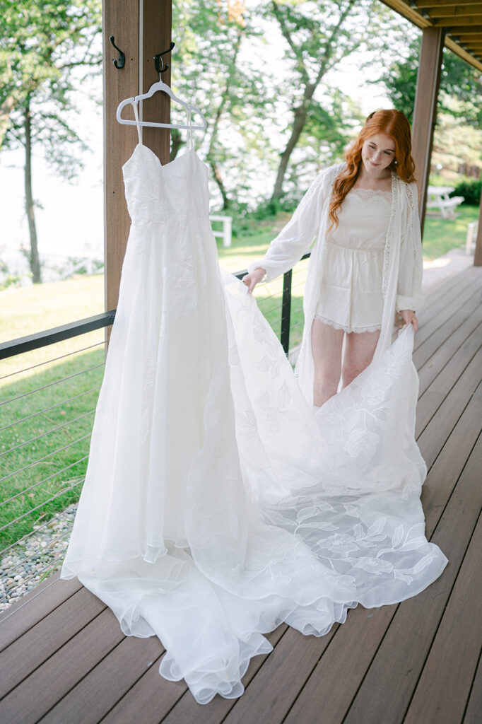 Bride admiring her wedding dress on the porch while getting ready. 