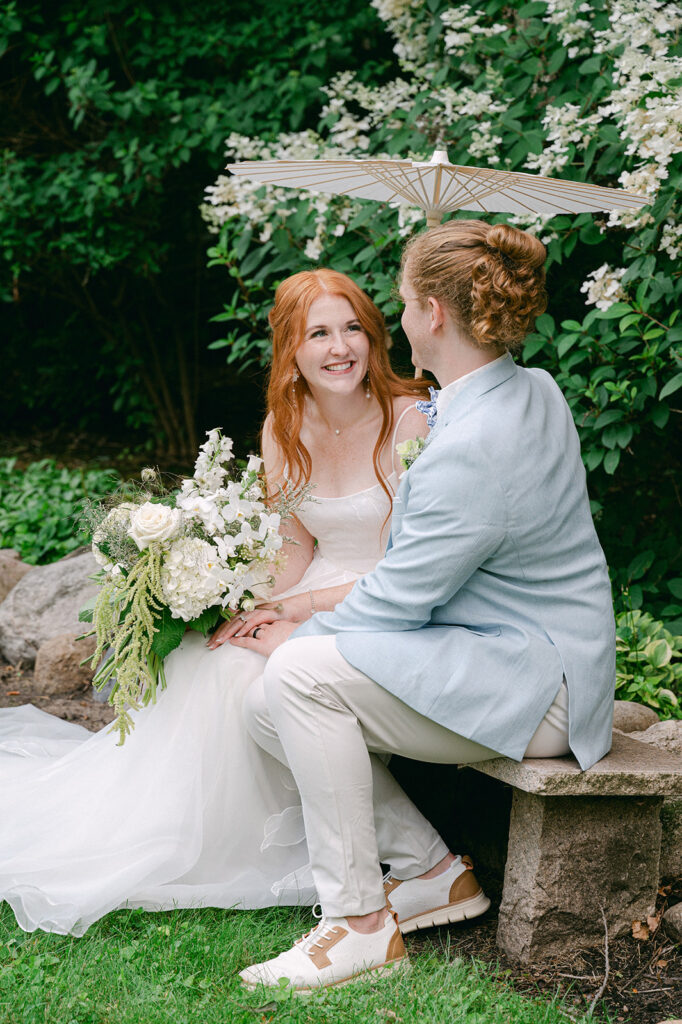 Stunning portrait of the couple in the garden, the bride's white floral bouquet and soft sunlight creating a dreamy atmosphere.