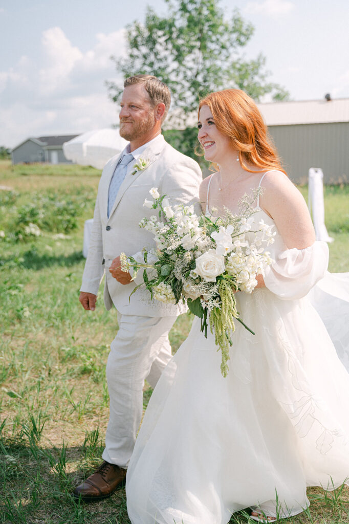 Bride walking down the aisle with her dad at an outdoor wedding in Minnesota. 