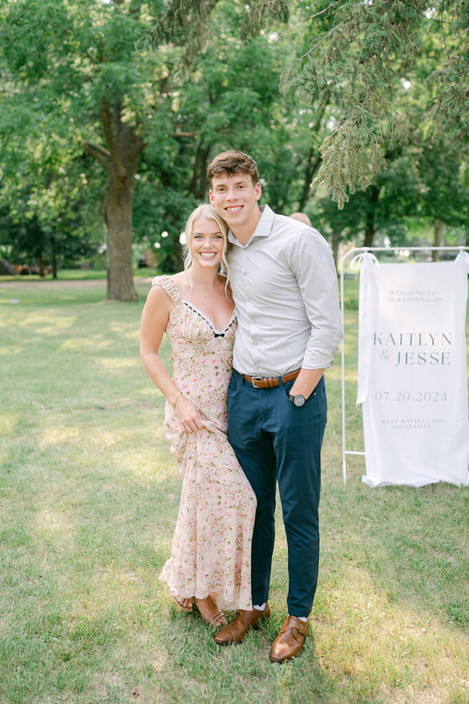 Wedding guests posing by a fabric welcome sign at a garden party wedding in Minnesota. 