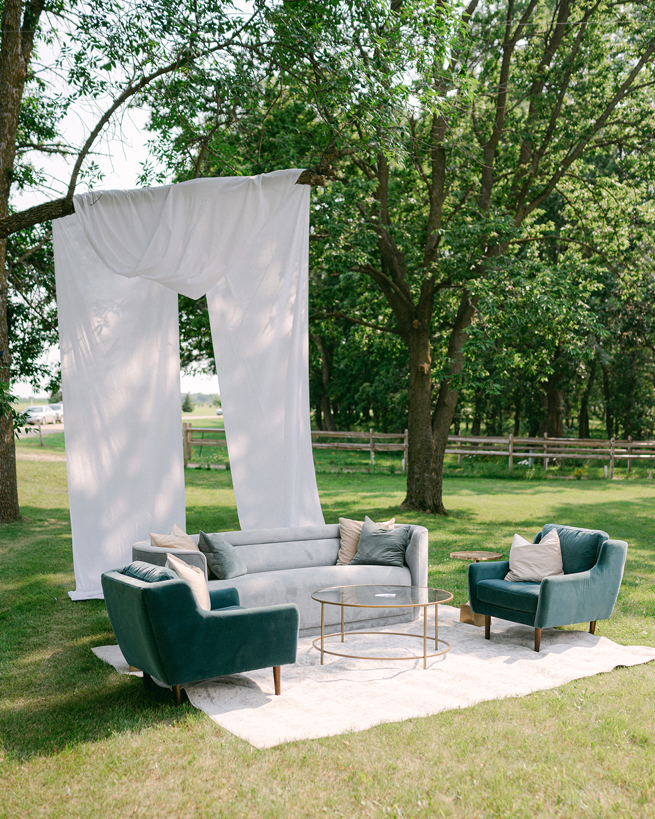 Outdoor wedding cocktail hour lounge area with velvet couches, and white dropcloth. 