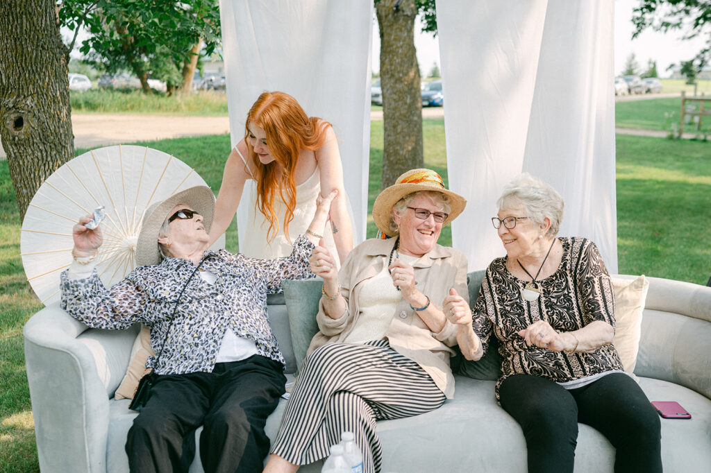 Bride greeting three older women sitting on a couch at cocktail hour. 