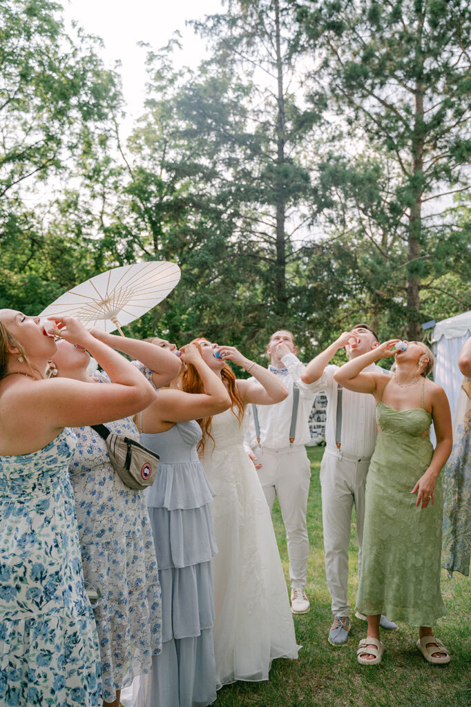 Bride and groom taking a shot with their wedding party at their summer garden party wedding. 