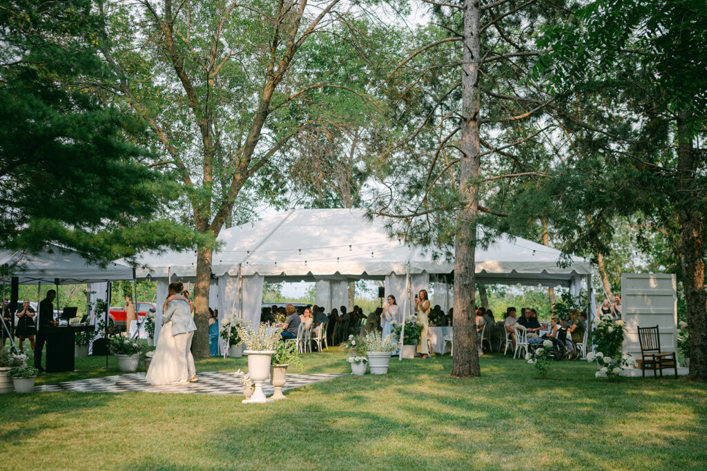 Bride and groom sharing their first dance on a checkered dance floor at their tented outdoor reception. 