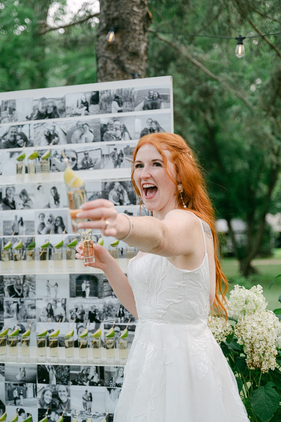 Bride holding out a tequila shot for her guest at her garden party wedding. 