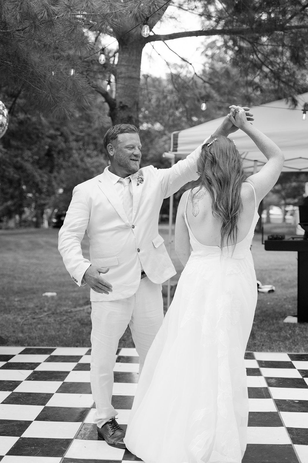 Father-daughter first dance on a checkered dance floor. 