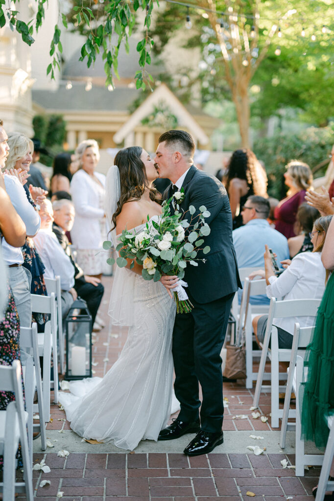 Wedding ceremony bride and groom recessional kiss captured by Sarah Woods Photography.