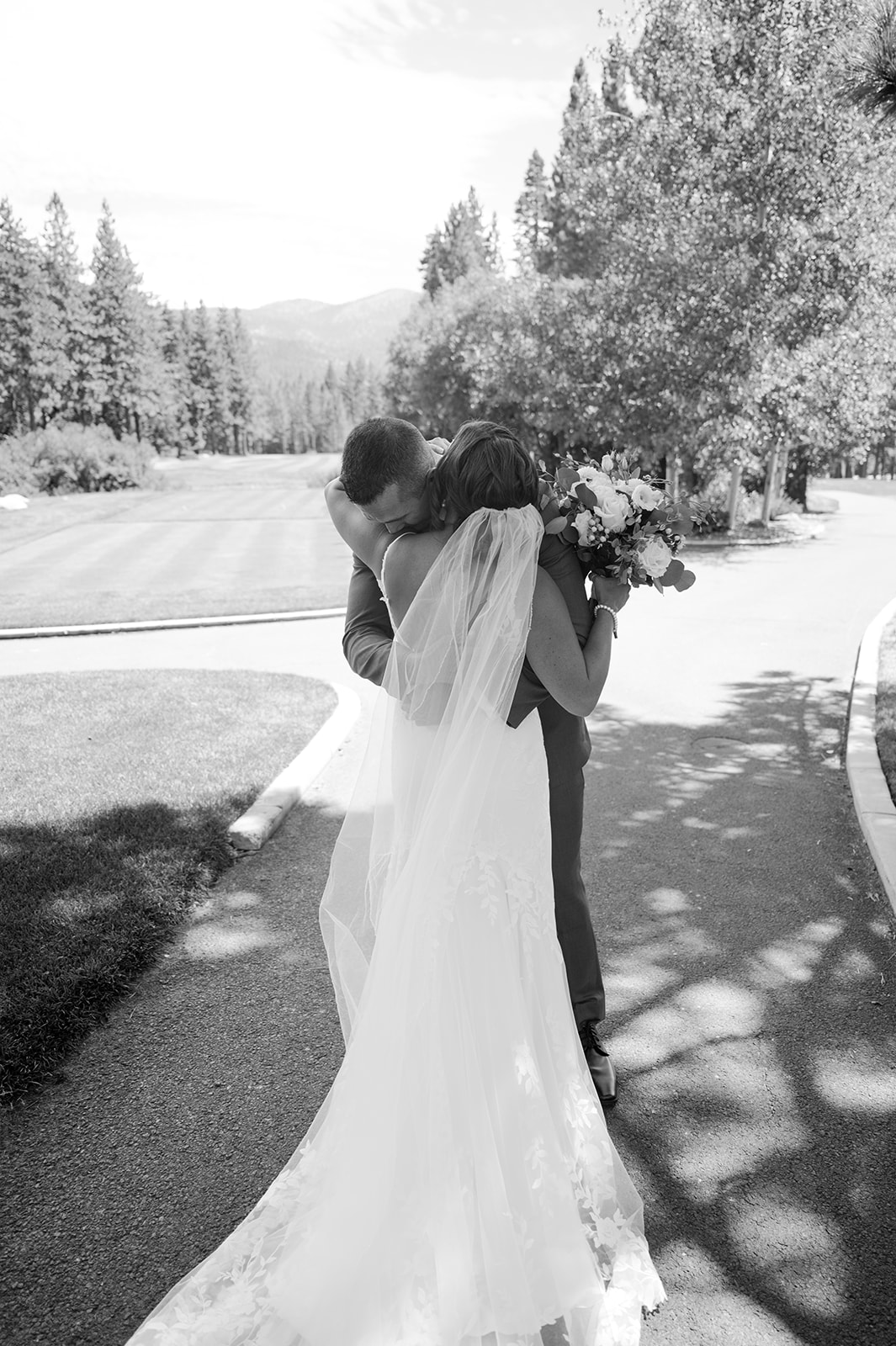 Candid bride and groom first look surrounded by summer greenery and mountain views.