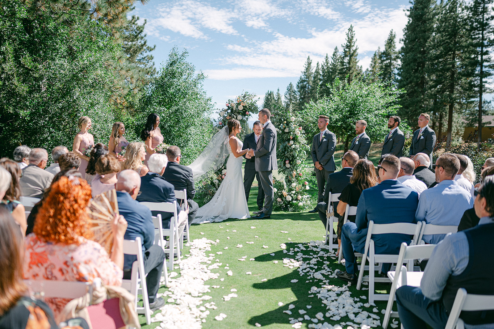 Stunning floral arch sets the scene for an intimate Lake Tahoe wedding ceremony with a petal-lined aisle.