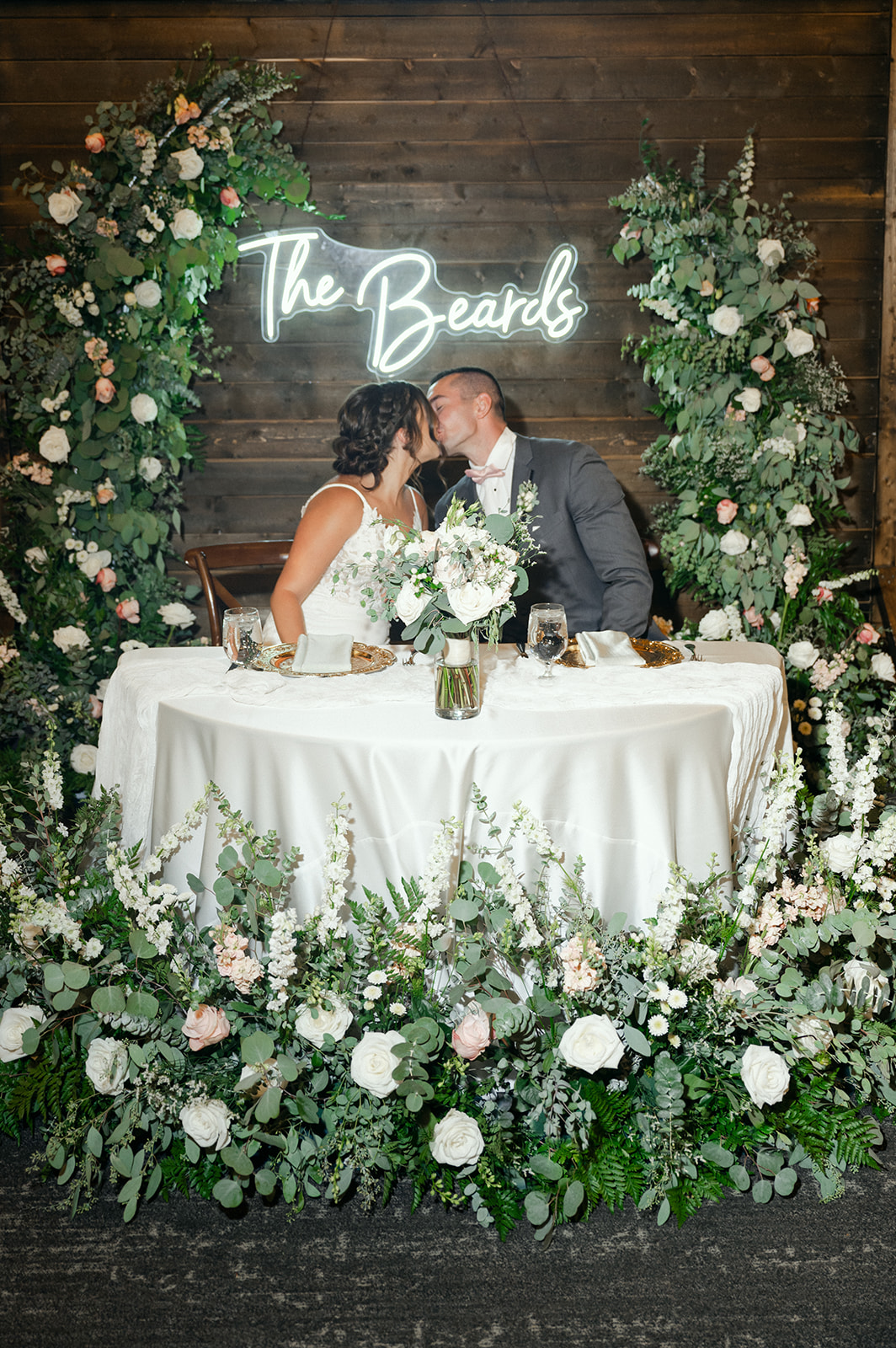 Bride and groom sweetheart table with repurposed floral arch. 