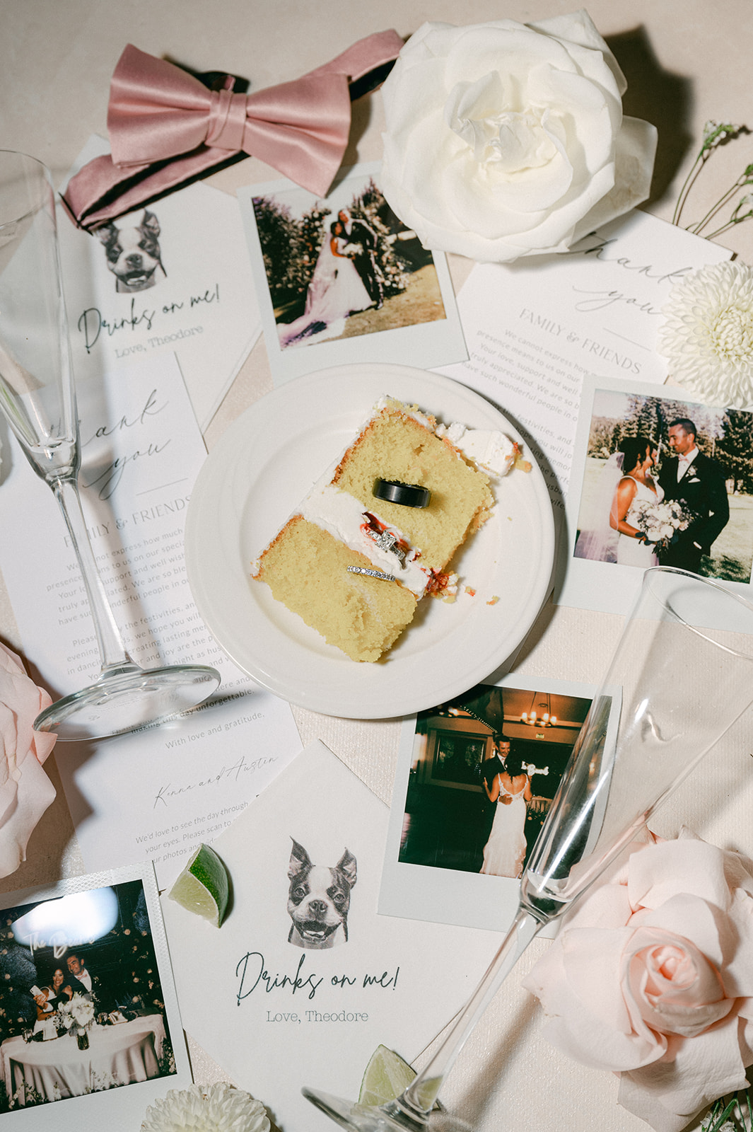 Elegant late night wedding flat lay with napkins, cake slice, rings, polaroids, champagne glasses and flowers. 