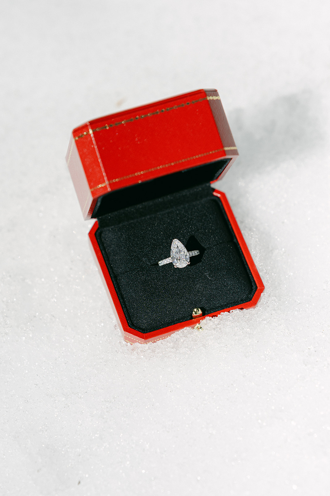 Red ring box and pear shaped silver diamond engagement ring. Proposal photoshoot in Lake Tahoe.
