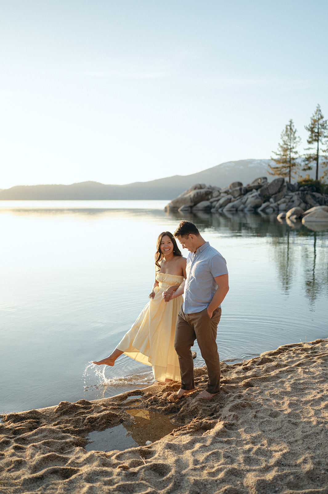 Woman kicking up water at Sand Harbor, Lake Tahoe during a sunset engagement session.