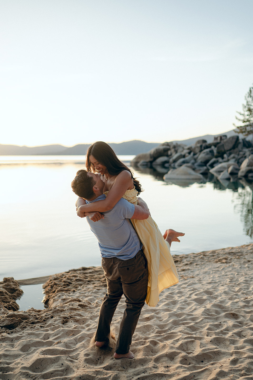 Couple hugging on the beach at Sand Harbor after their surprise proposal.