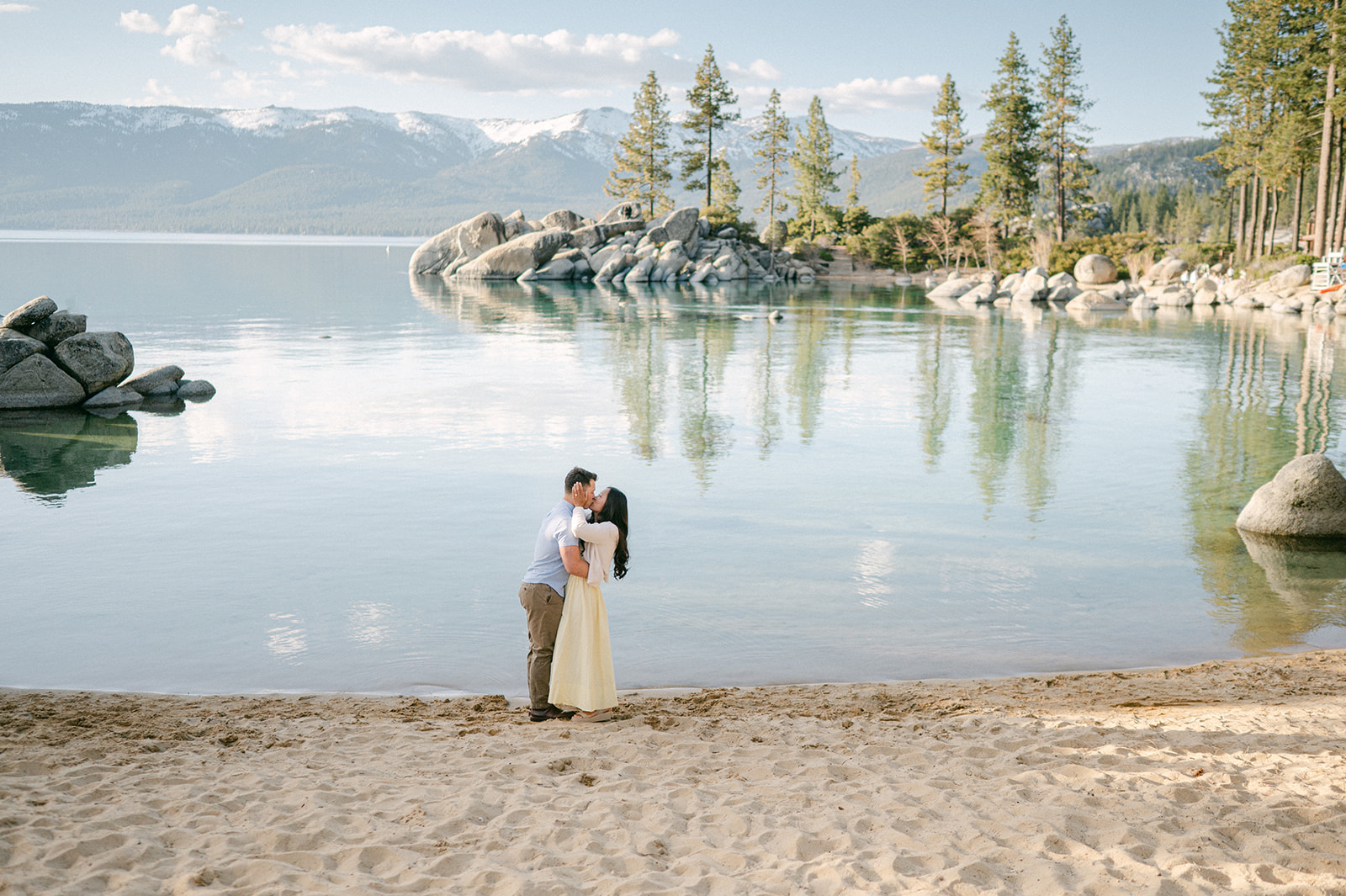 Couple kissing on the shores of Sand Harbor after their surprise proposal.