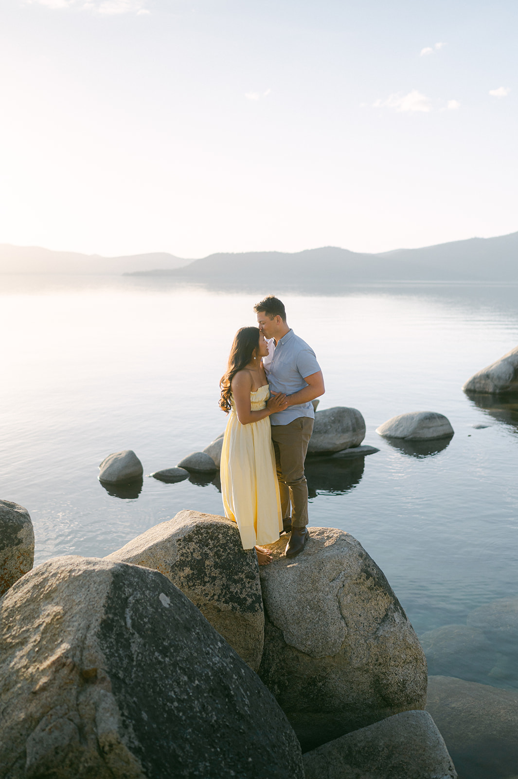 Couple standing on the iconic boulders at Sand Harbor—Lake Tahoe engagement photoshoot.