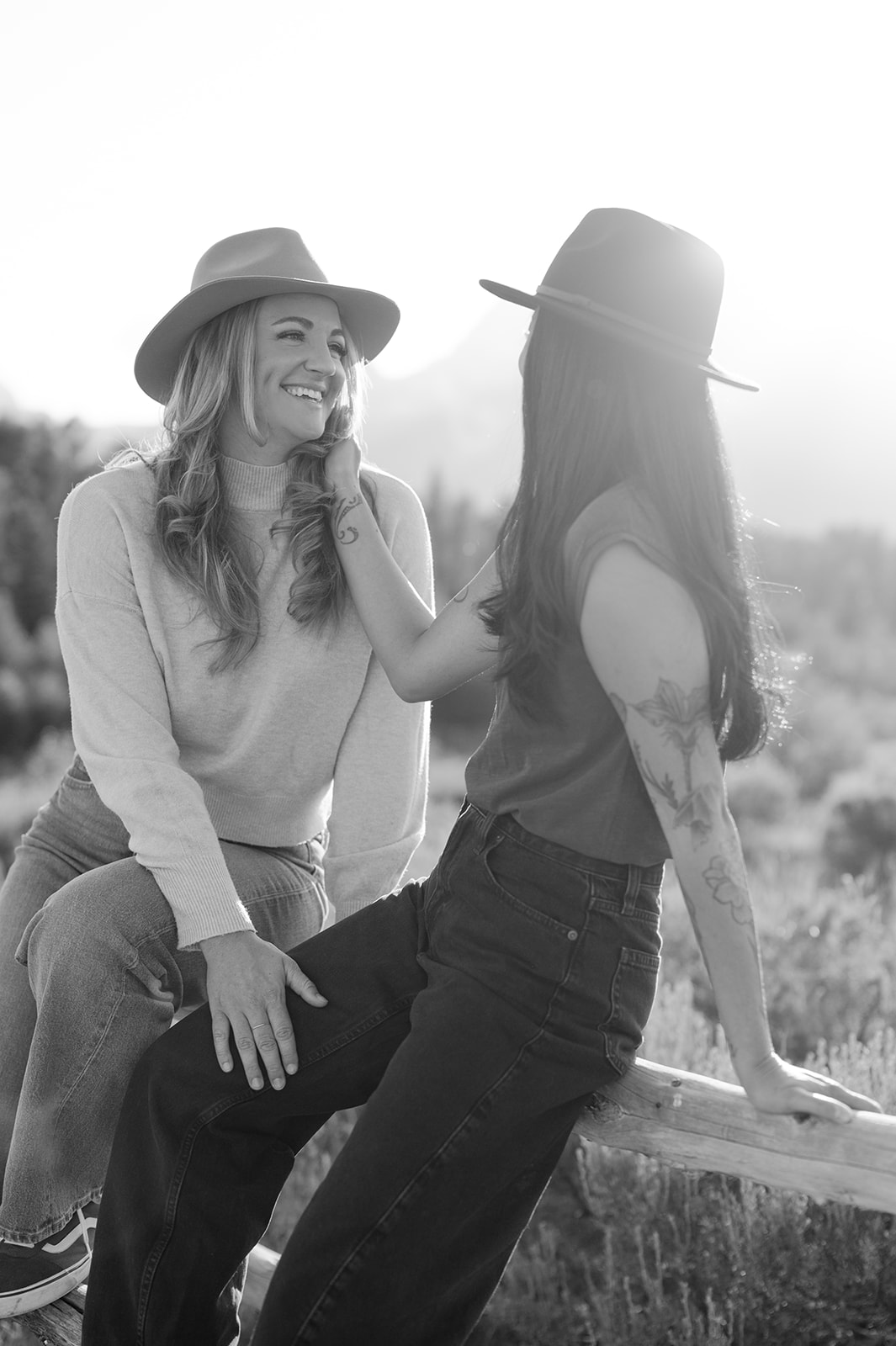 Western-inspired couple’s session with cowboy hats and relaxed, natural poses on a log fence.
