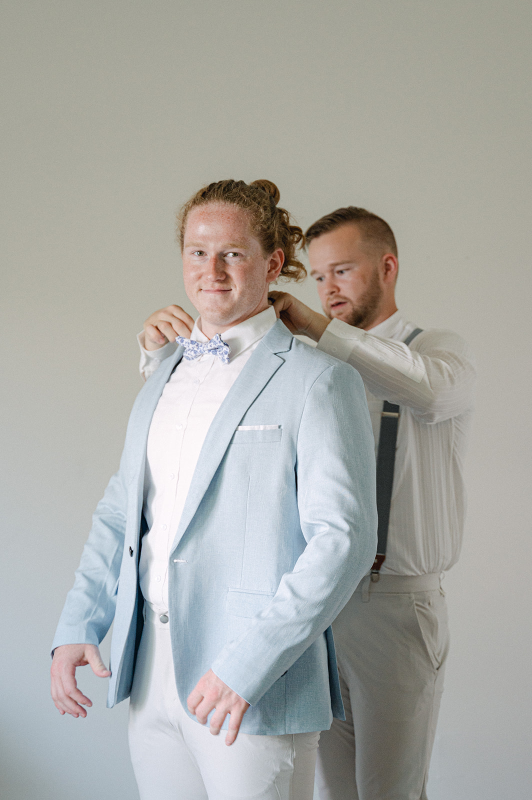 Groomsmen helping groom fix his collar.