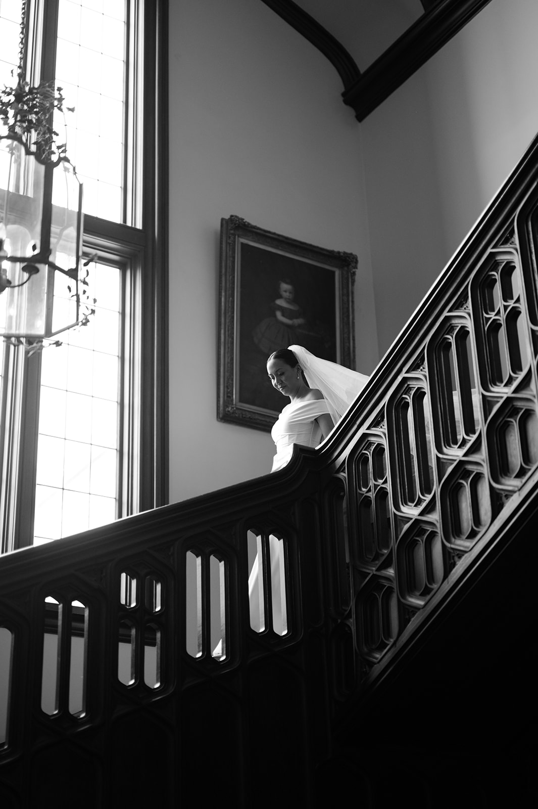Bride walking down elegant staircase at Kohl Mansion wedding.