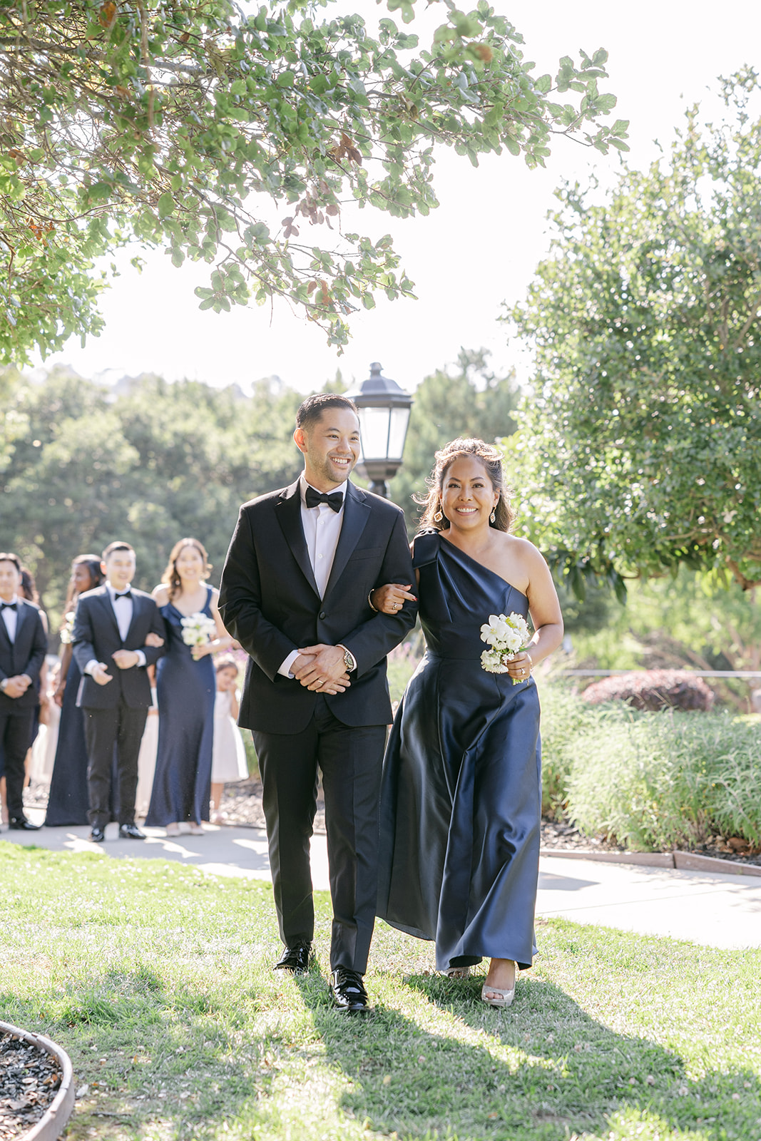 Bridesmaids and groomsmen walking down the aisle at outdoor ceremony in California. 