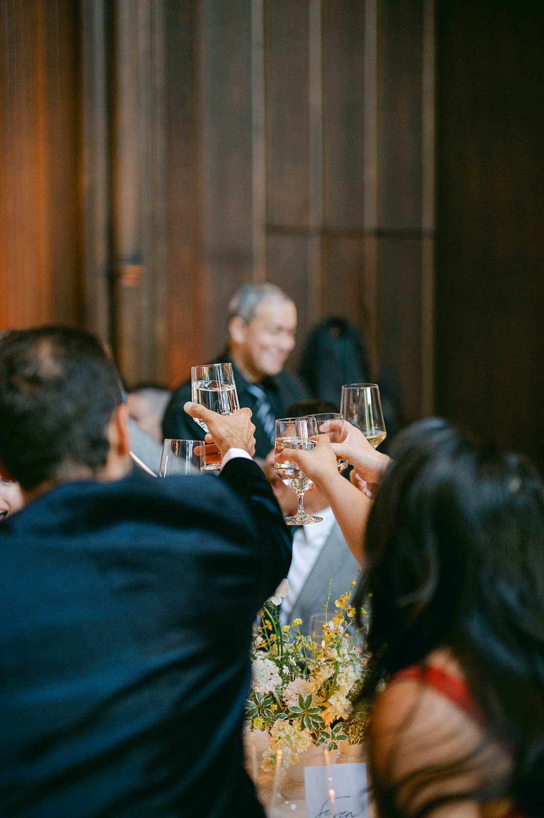 Guests clinking glasses during dinner at Kohl Mansion reception.