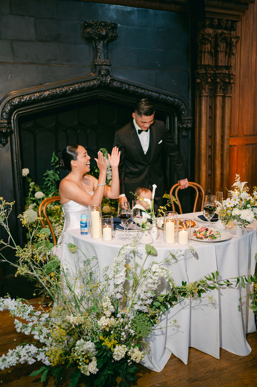 Bride and groom at sweetheart table with fireplace backdrop.