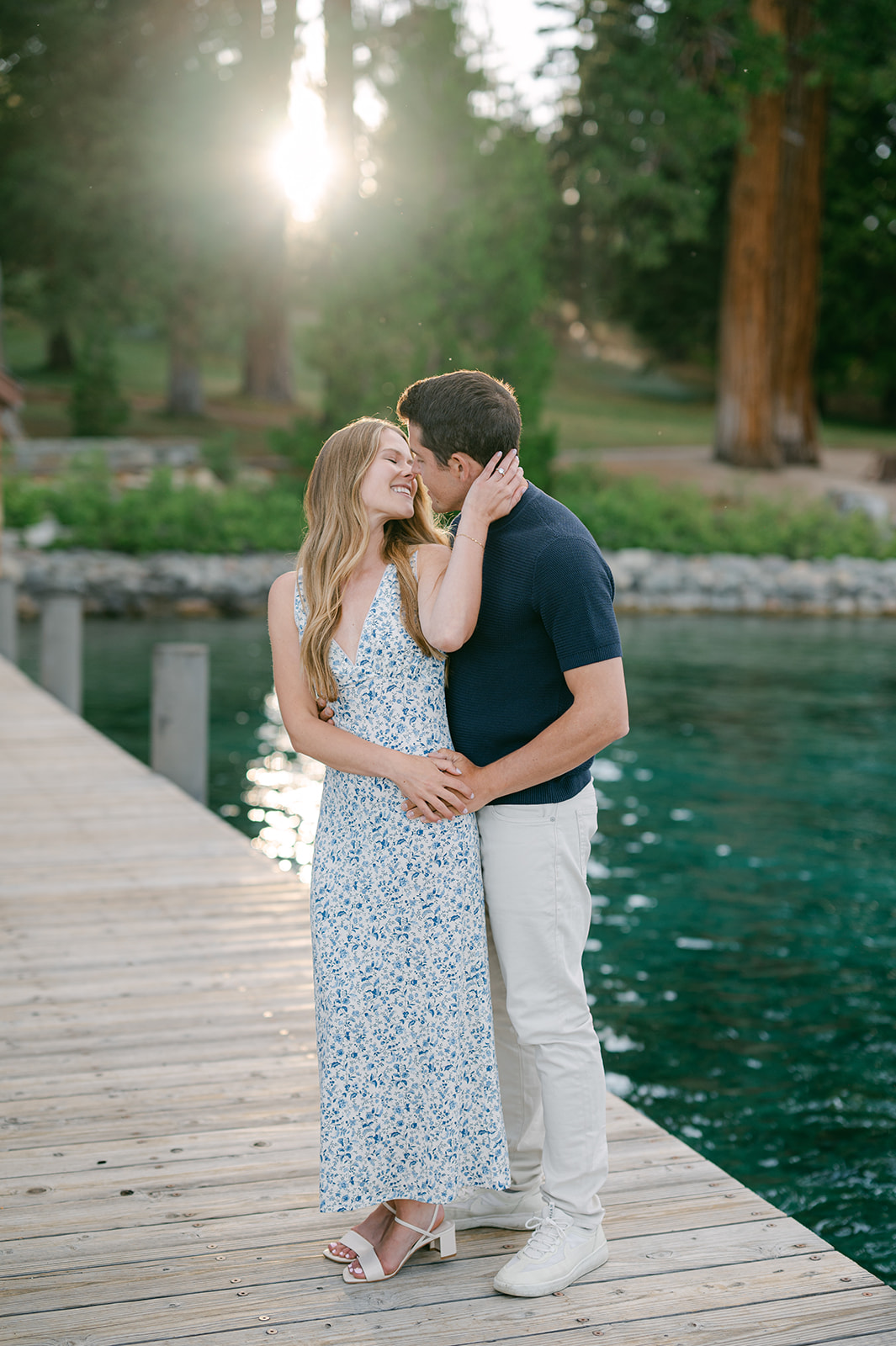 Bride-to-be leaning in for a kiss from behind on a wooden dock | Lake Tahoe timeless engagement photography.