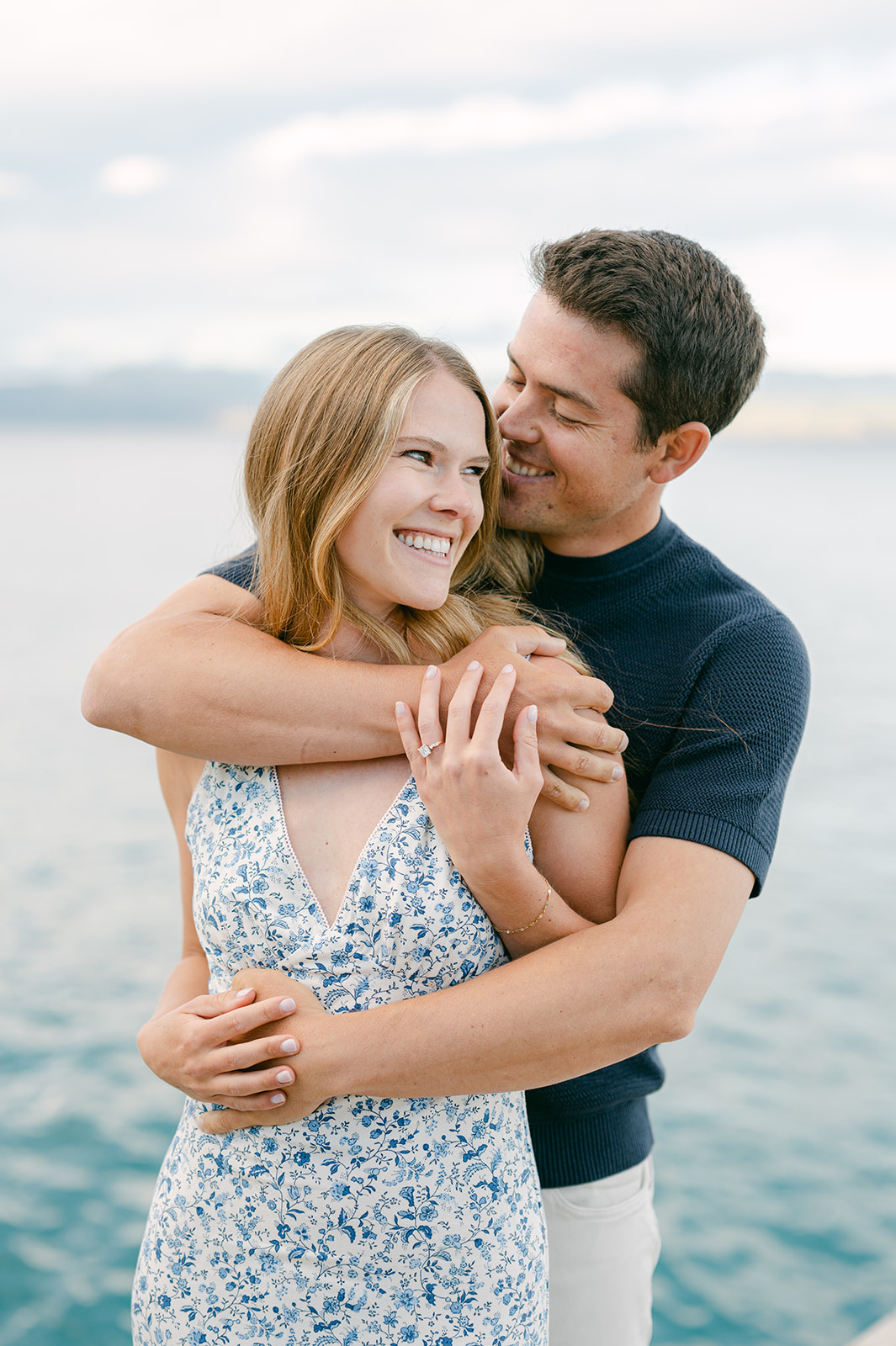 Groom hugging bride from behind with Lake Tahoe in the background. 