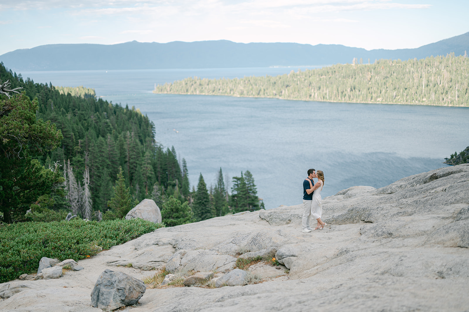 Couple sharing a kiss with Lake Tahoe in the distance.