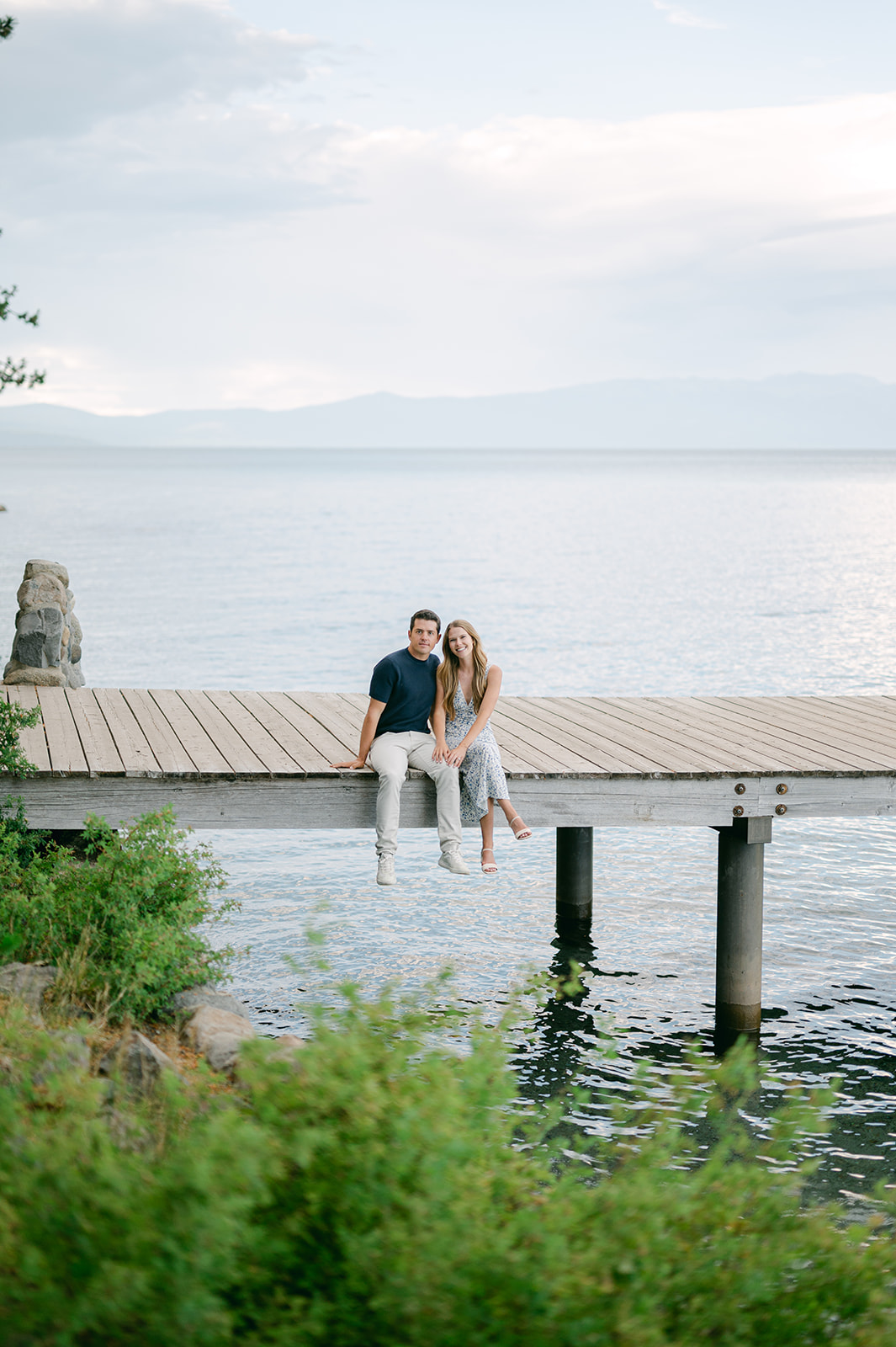 Couple sitting at the edge of the dock | romantic engagement photo Tahoe.