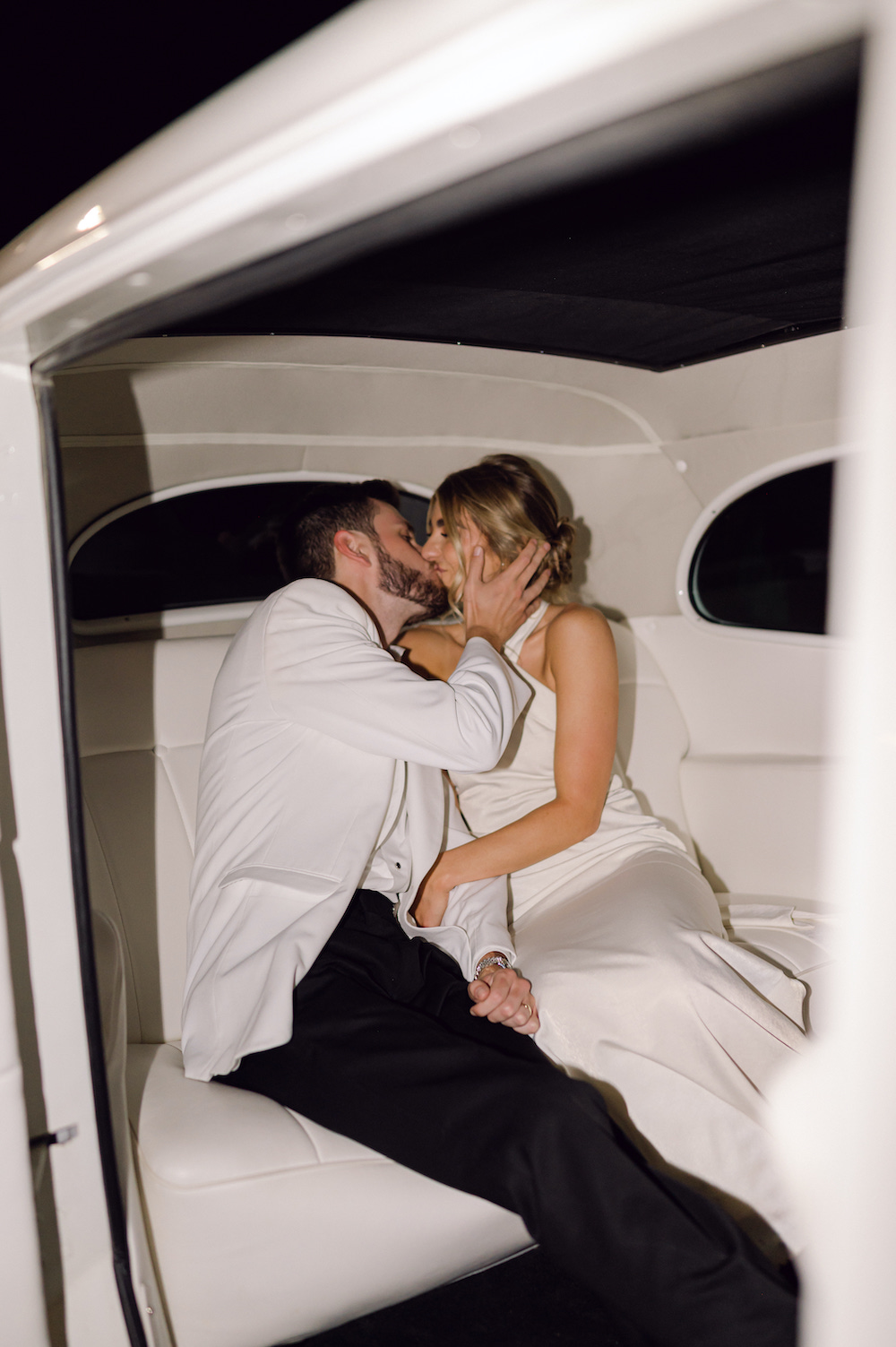 Bride and groom sharing a kiss in their vintage getaway car.