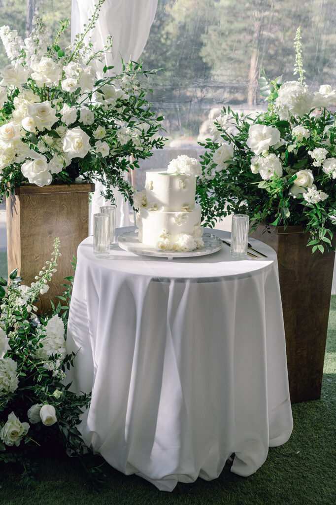 Wedding cake table surrounded by lush white florals. Lake Tahoe luxury wedding.