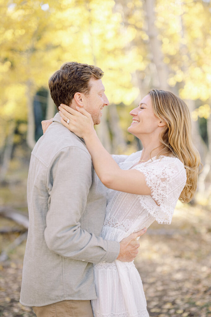 Couple hugs in front of golden aspen trees during engagement photos.