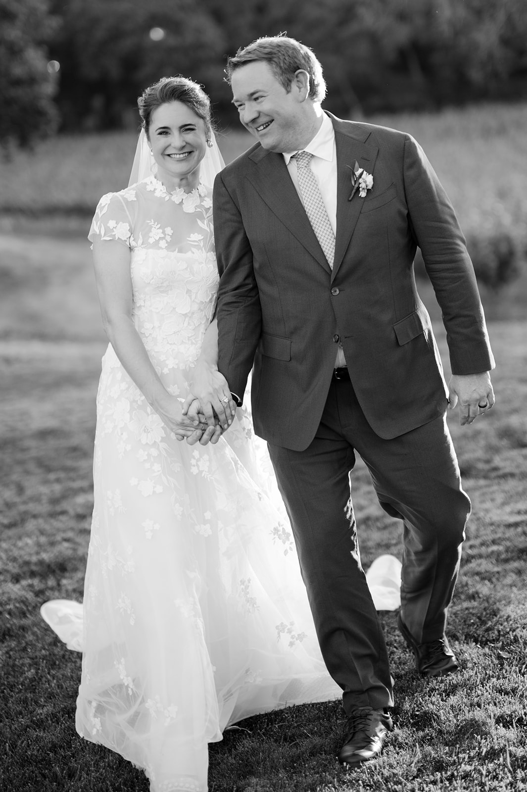 Bride and groom holding hands during golden hour vineyard portraits.