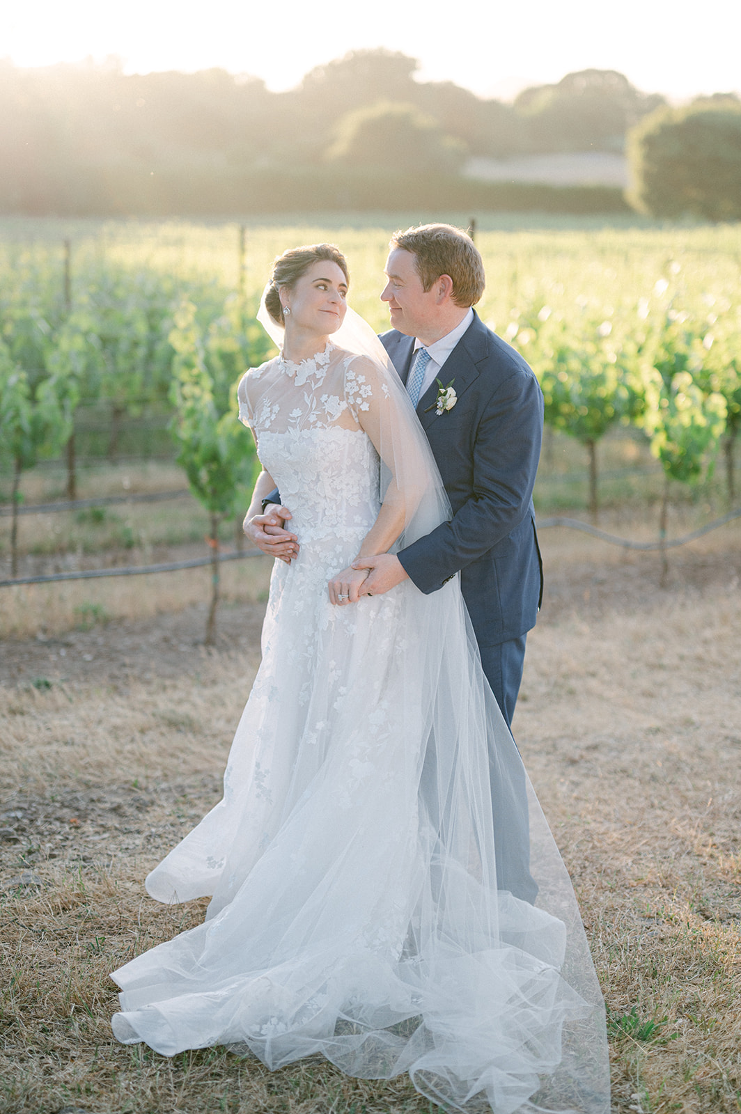 Couple embracing with vineyard views in Napa Valley.