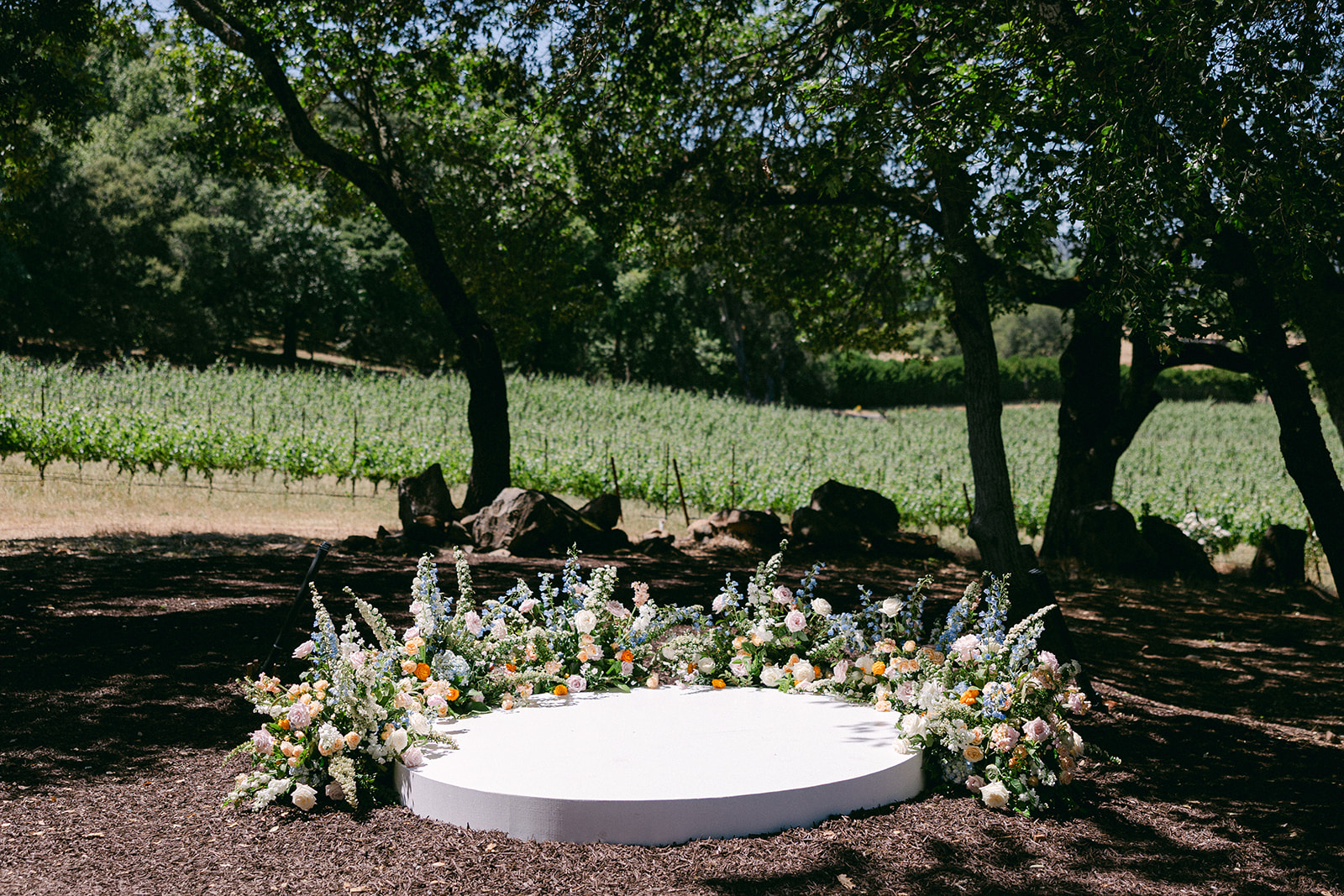 Round wedding ceremony stage with a grounded floral arch. 
