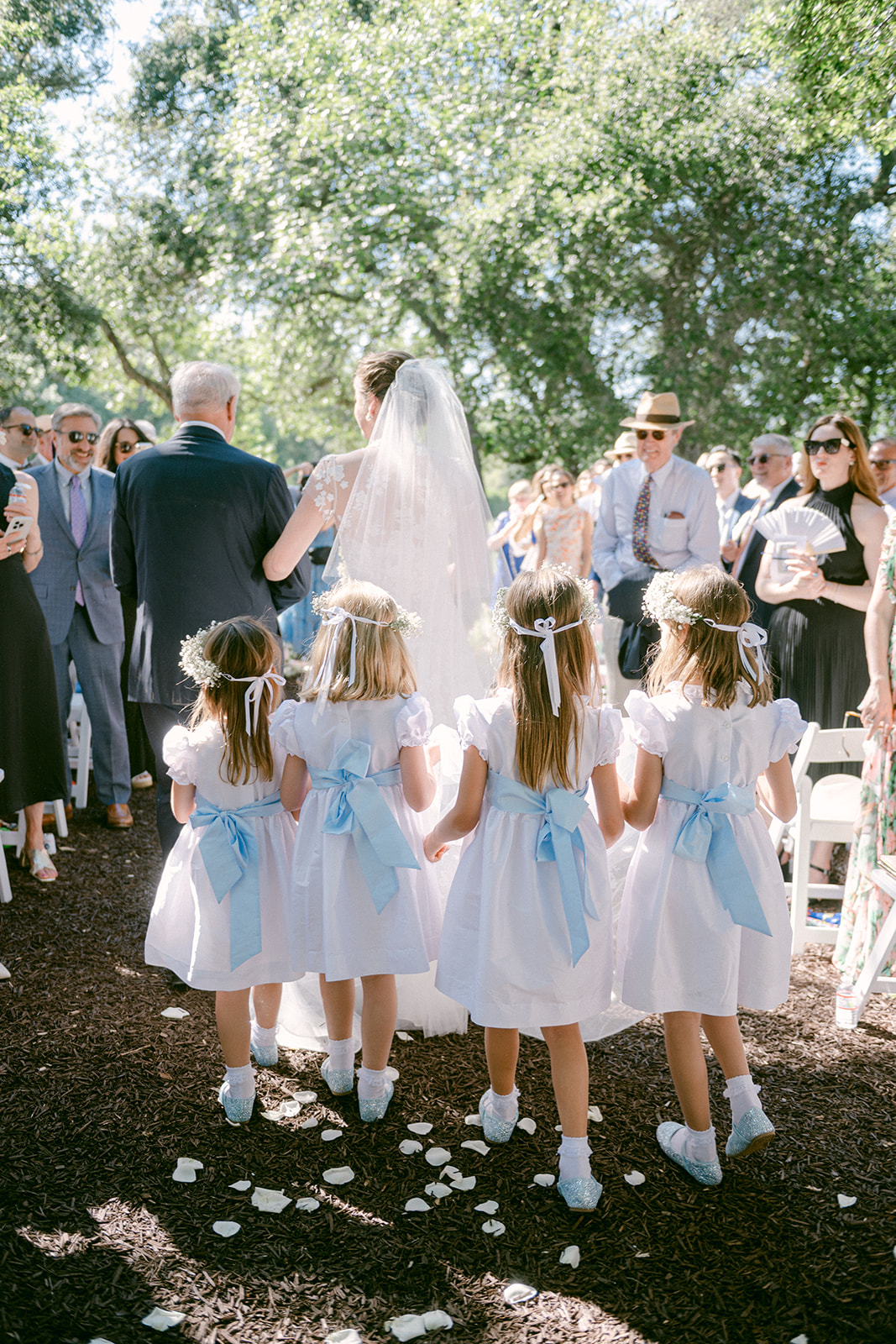 Bride walking down the aisle with nieces carrying her train.