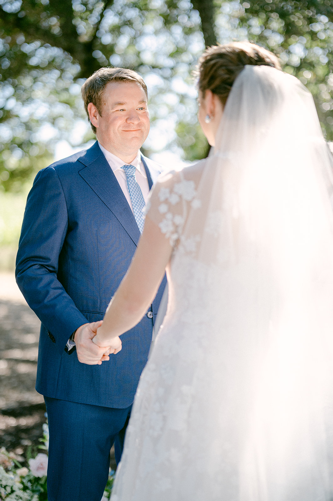Bride and groom exchanging vows under vineyard trees.