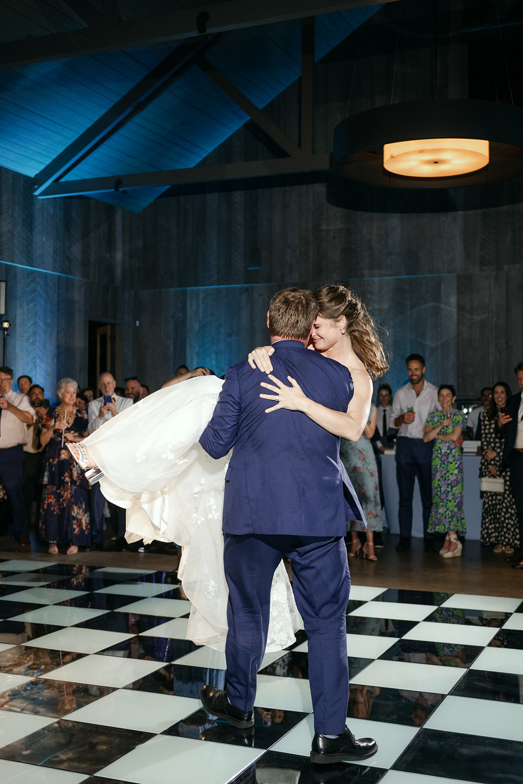 Bride and groom first dance on a checkered dance floor. 