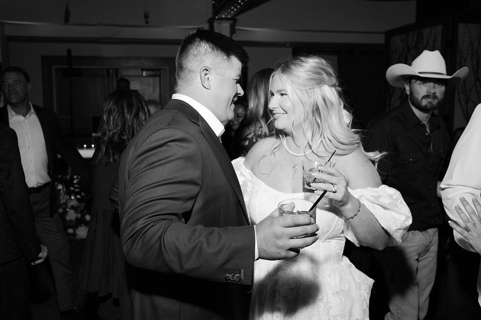 Bride and groom smiling and holding cocktails during their reception.