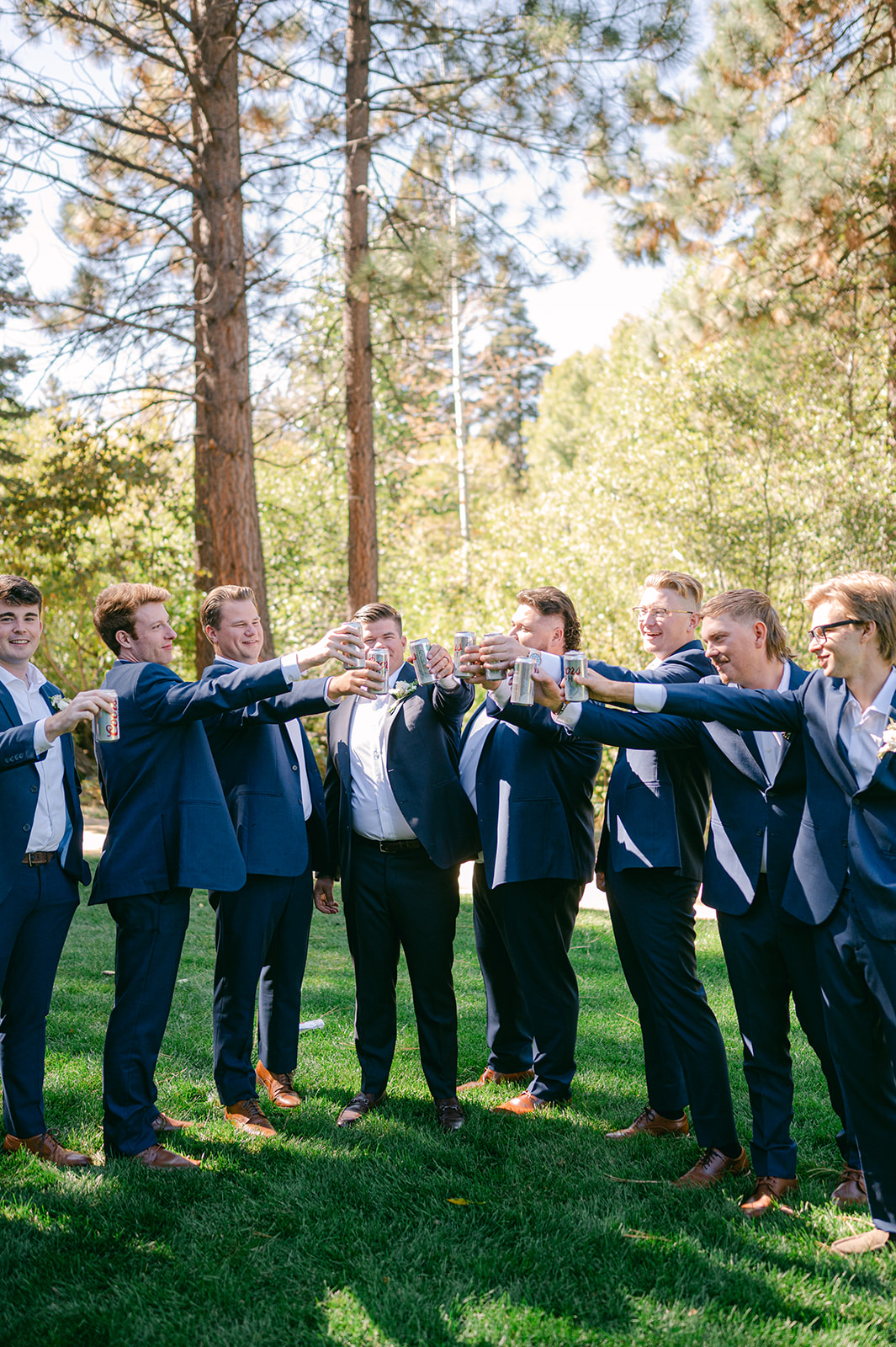 Candid moment of the groom and his groomsmen sharing a beer toast.