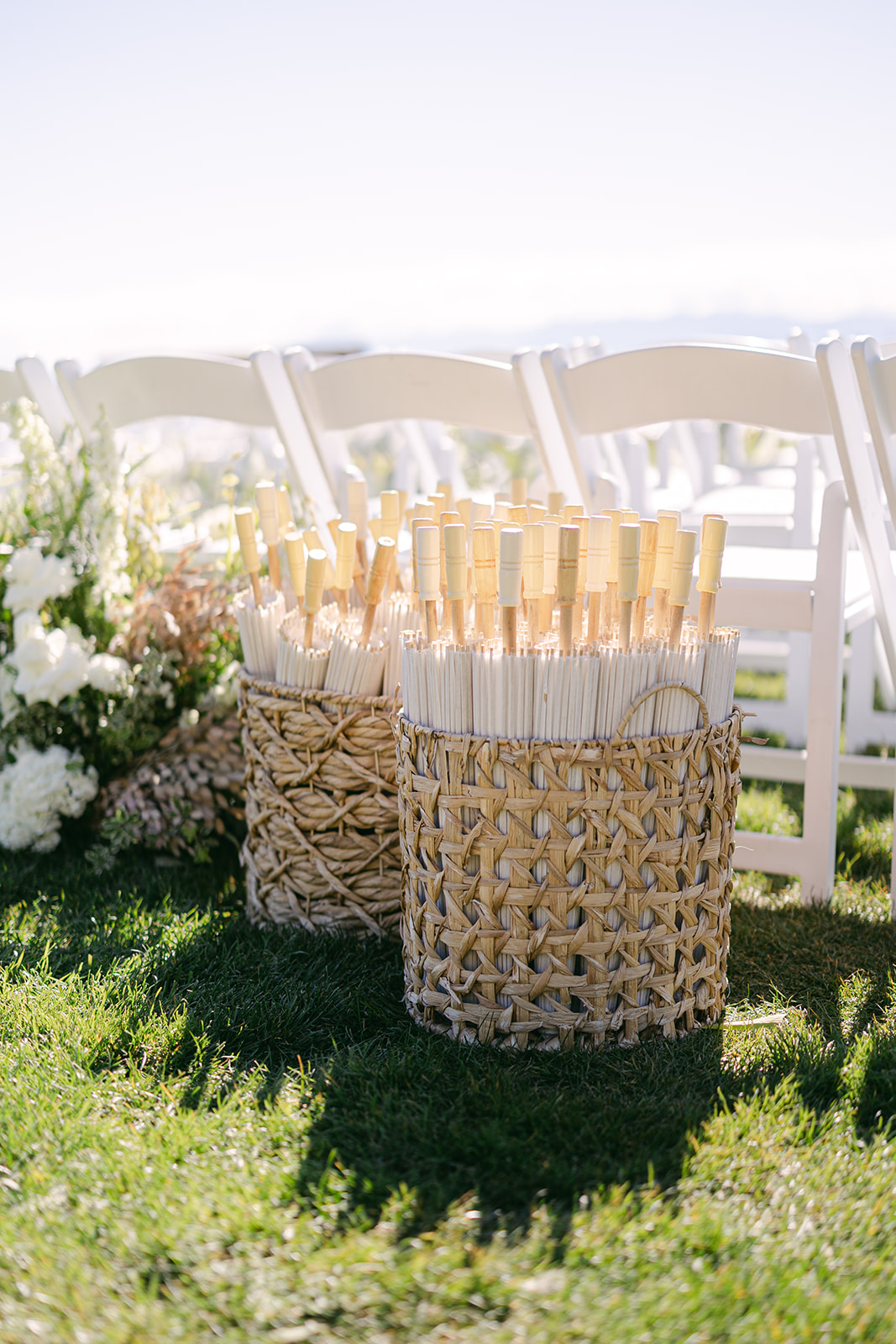 Ceremony details including vintage parasols, floral arrangements and white chairs.