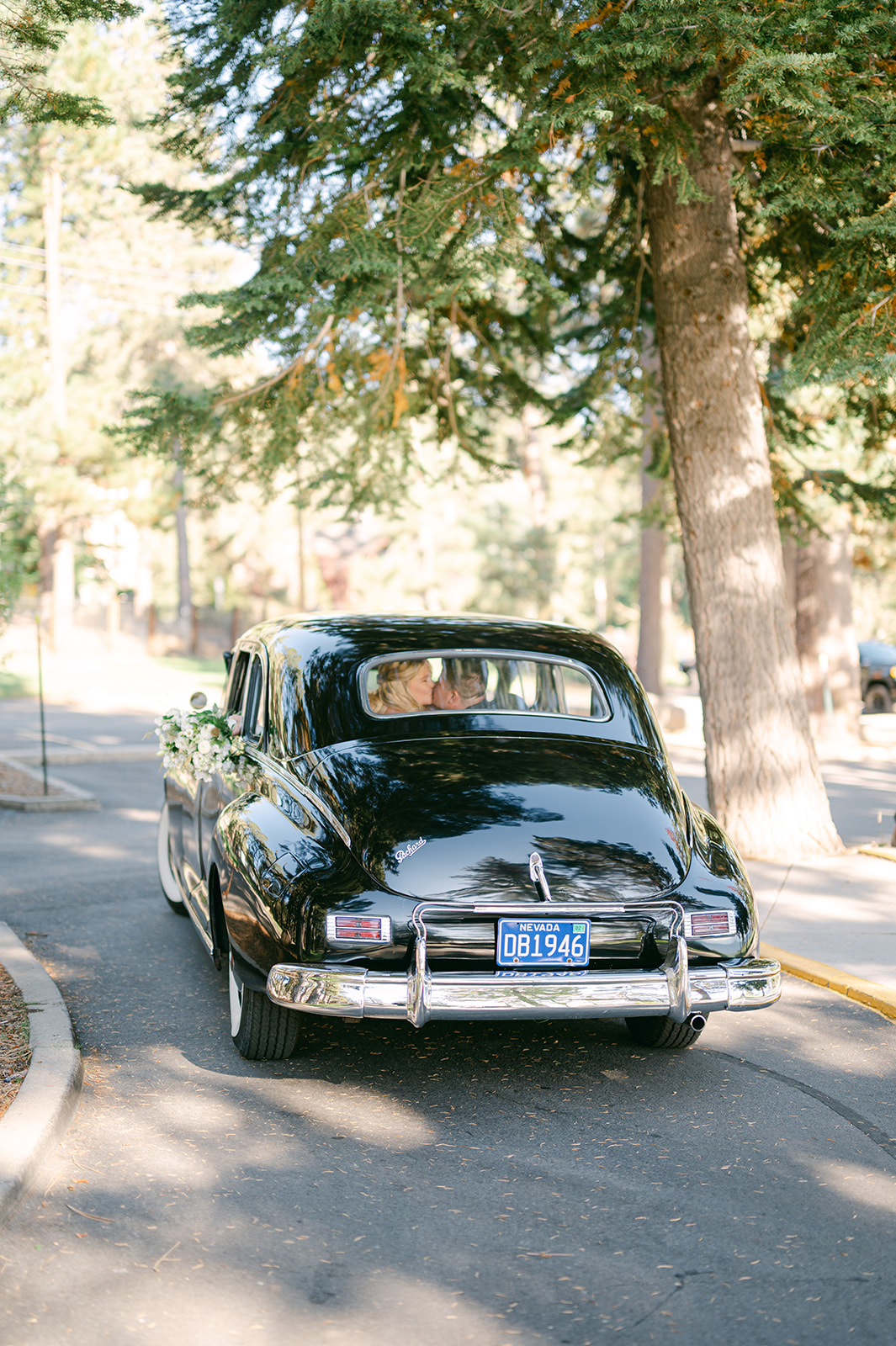 Bride and groom kissing inside of a vintage Packard car.