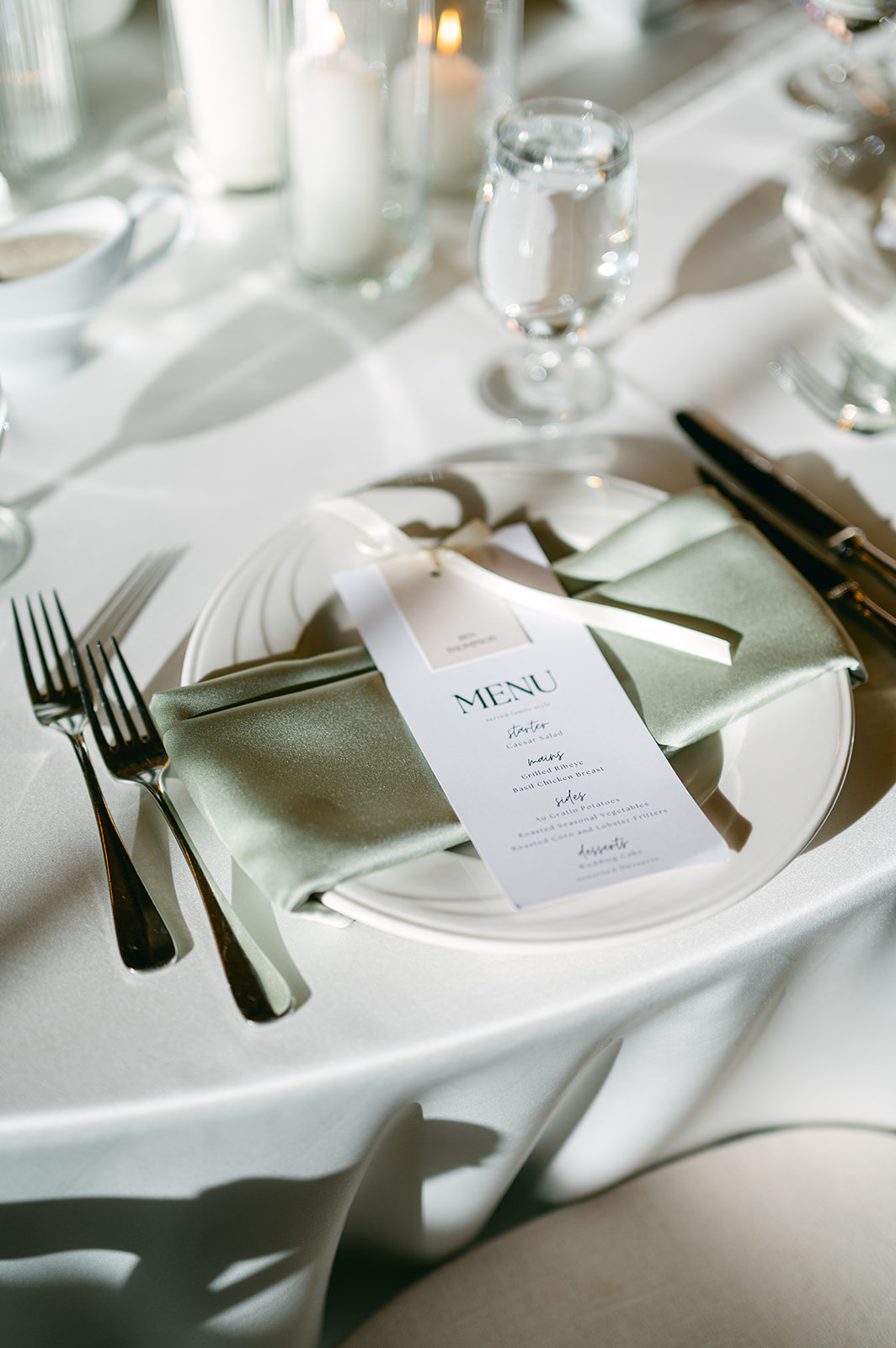 Wedding table setting details with sage green napkins and simple menus tied with a bow.