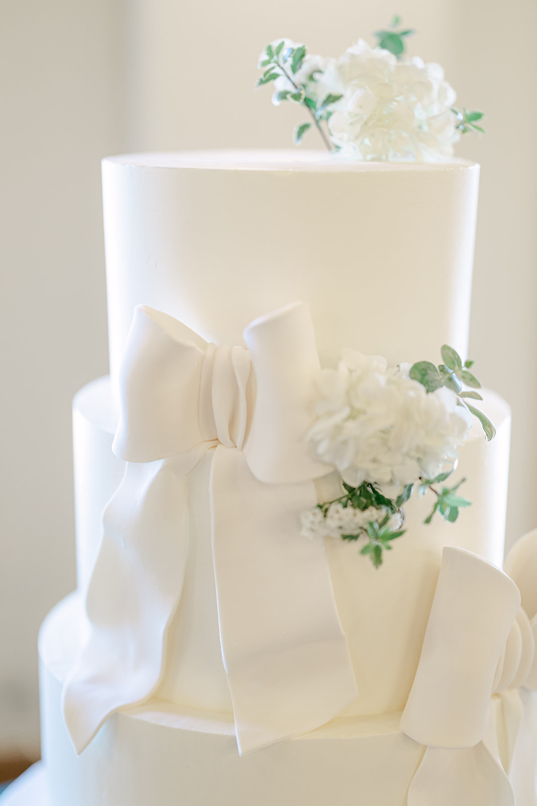 White wedding cake with bows and floral details.