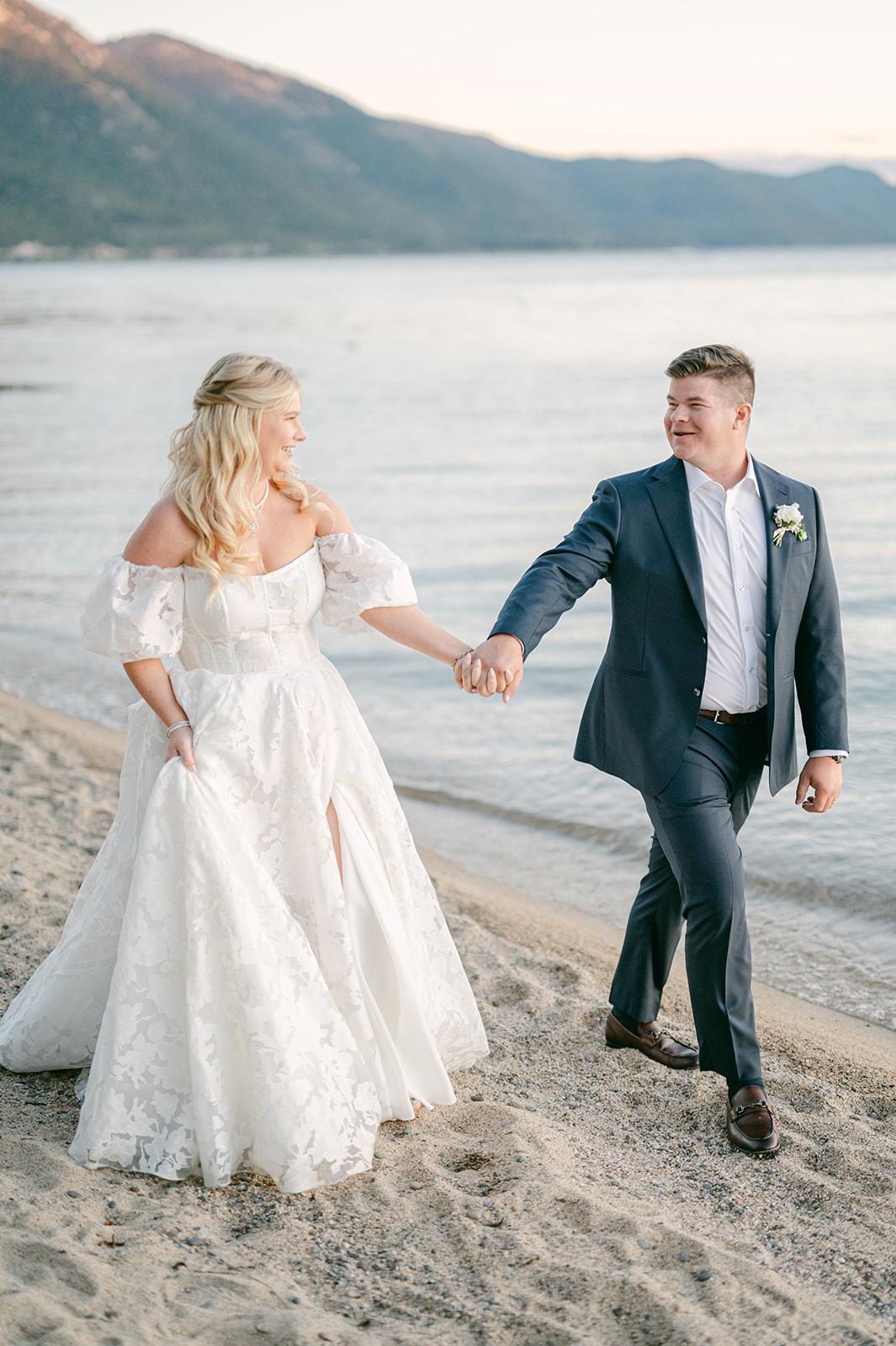 Couple holding hands and walking along the lake at sunset.